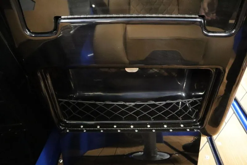 Slide: The Image of 2024 Yamaha Boats 222XE storage compartment with netting and sleek black finish. - 38