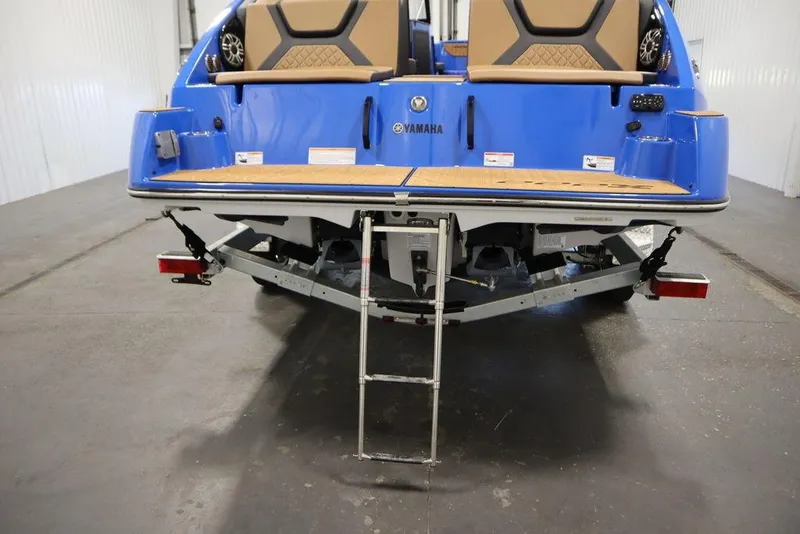Slide: The Image of 2024 Yamaha Boats 222XE rear view with swim platform and ladder in a showroom. - 56