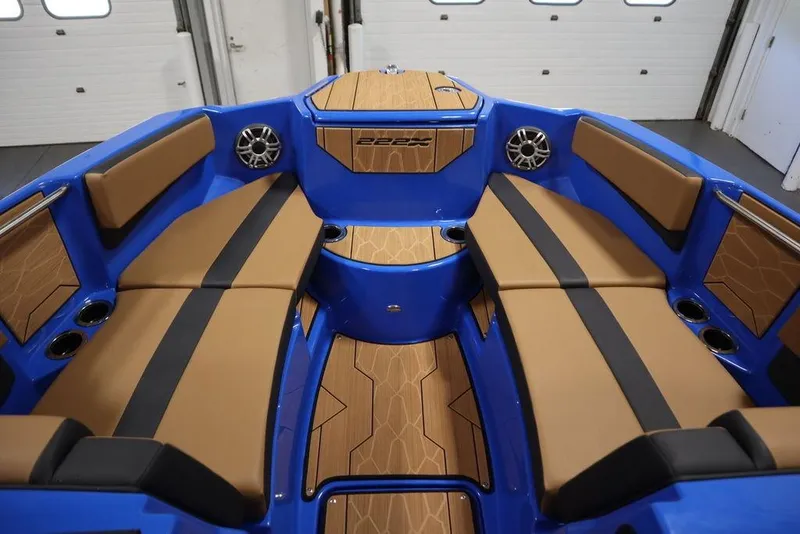 Slide: The Image of 2024 Yamaha Boats 222XE interior with blue and tan seating, cup holders, and speakers. - 9