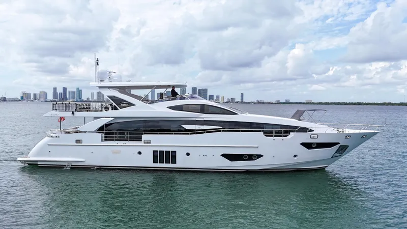 The Image of 2017 Azimut 95 Raised Pilothouse yacht on calm water with city skyline backdrop. - 1
