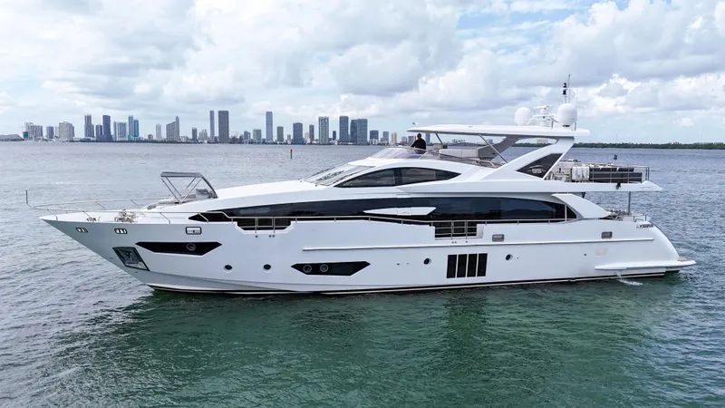 Slide: The Image of 2017 Azimut 95 Raised Pilothouse yacht on calm water with city skyline backdrop. - 10