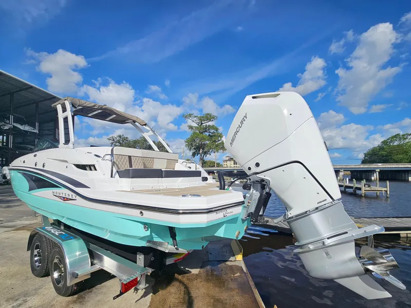 Slide: The Image of 2025 Monterey M-65 boat with outboard motor on trailer by the water. - 3