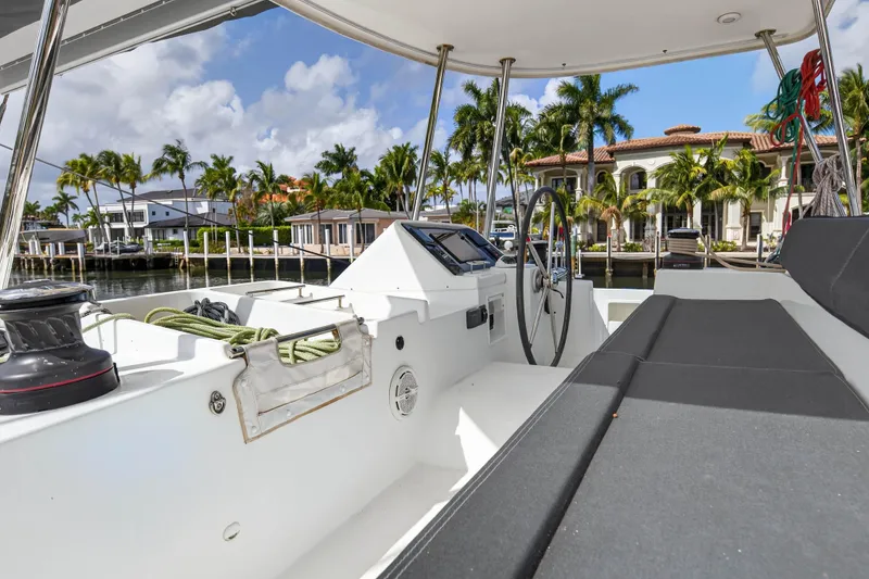 Slide: The Image of 2019 Lagoon 450 F yacht cockpit with luxurious waterfront view and palm trees. - 14