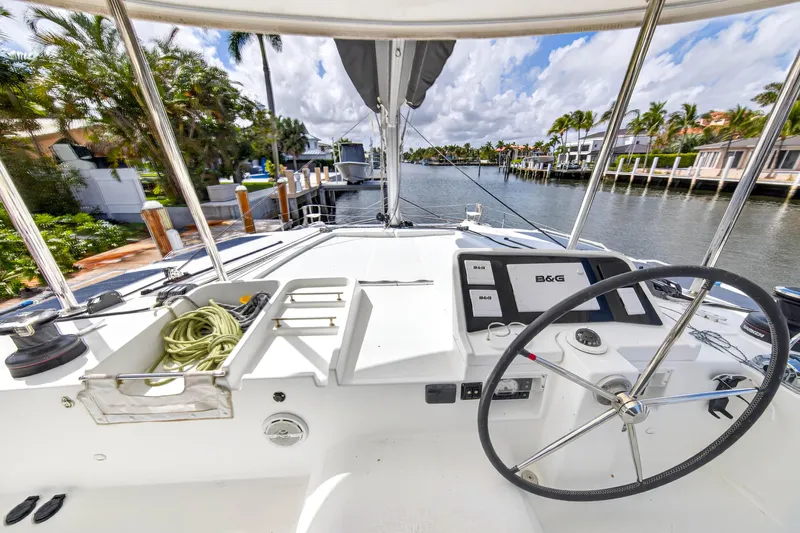 Slide: The Image of 2019 Lagoon 450 F yacht helm with navigation equipment, docked in a scenic canal. - 18