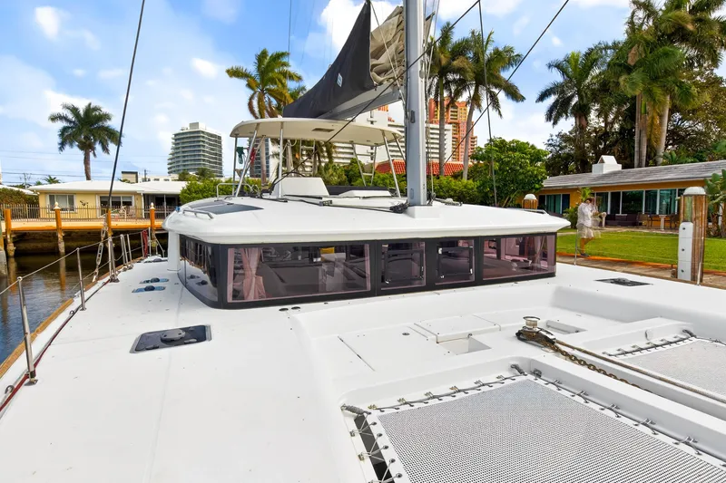 Slide: The Image of 2019 Lagoon 450 F catamaran docked near waterfront homes and palm trees. - 22