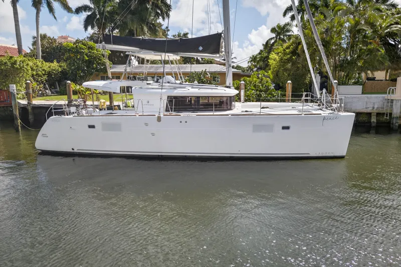 Slide: The Image of 2019 Lagoon 450 F catamaran docked by lush greenery and waterfront homes. - 3