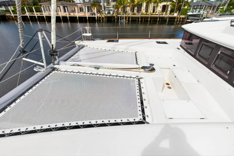 Slide: The Image of 2019 Lagoon 450 F catamaran deck with netting, docked by waterfront homes. - 30