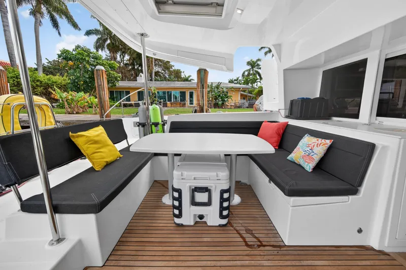 Slide: The Image of 2019 Lagoon 450 F yacht cockpit with cushioned seating, table, and colorful pillows. - 37