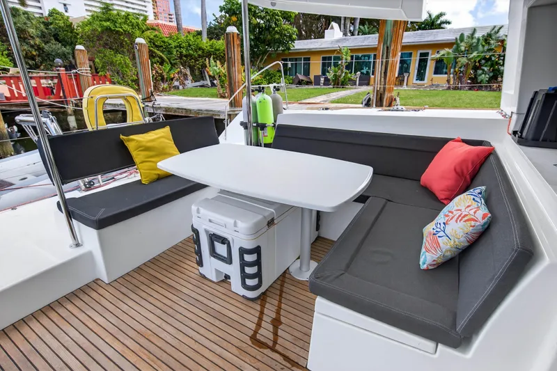 Slide: The Image of 2019 Lagoon 450 F yacht deck with cushioned seating and table, featuring colorful pillows. - 38