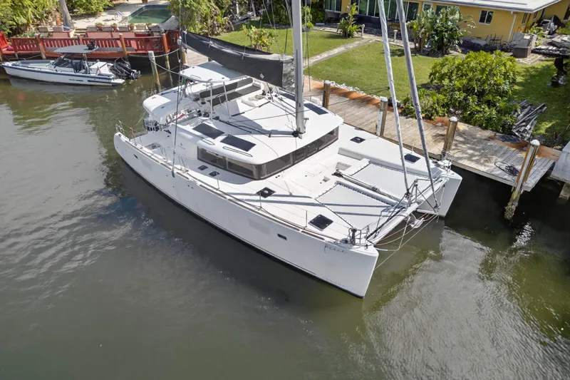 Slide: The Image of 2019 Lagoon 450 F catamaran docked by a waterfront home. - 4