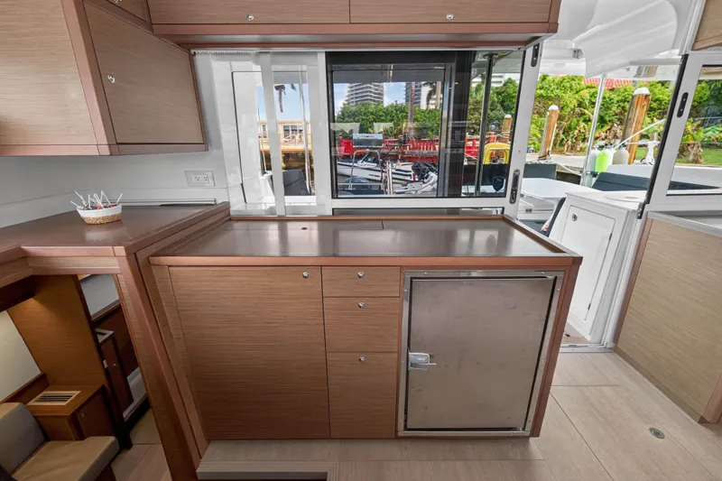 Slide: The Image of Interior of 2019 Lagoon 450 F yacht with modern wooden cabinetry and outdoor view. - 65