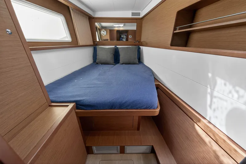 Slide: The Image of 2019 Lagoon 450 F cabin interior with blue bedding and wooden finish. - 82