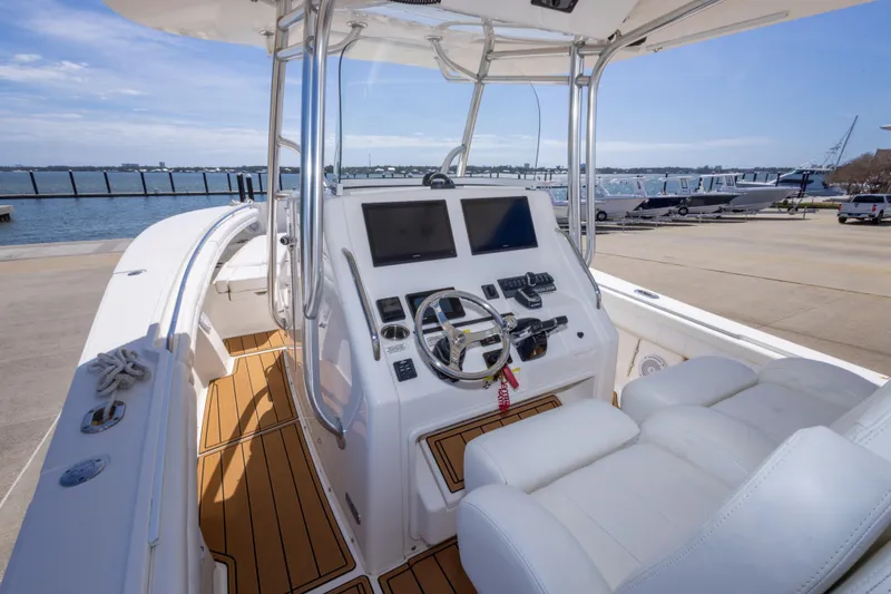 Slide: The Image of 2018 Regulator 31 boat cockpit with dual screens and white seating, docked by the water. - 26