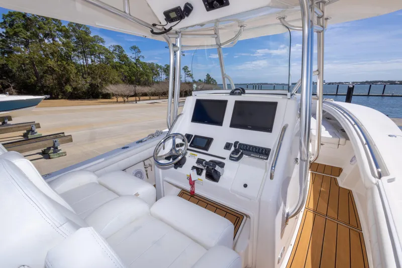 Slide: The Image of 2018 Regulator 31 boat cockpit with dual screens and white seating, docked by the water. - 27