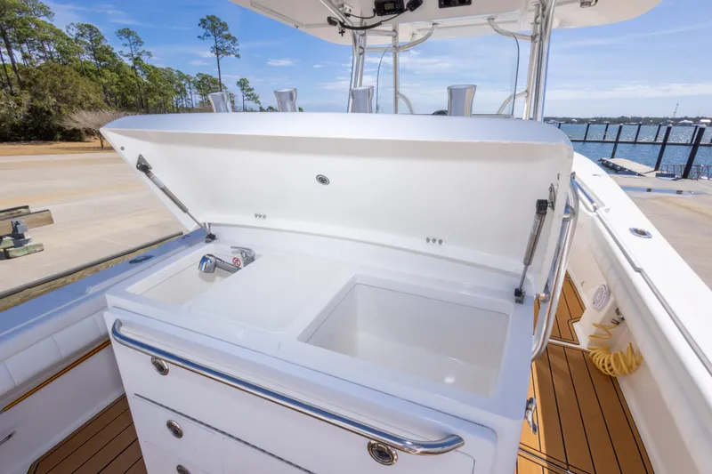 Slide: The Image of 2018 Regulator 31 boat with open storage compartment and sink, dockside view. - 32