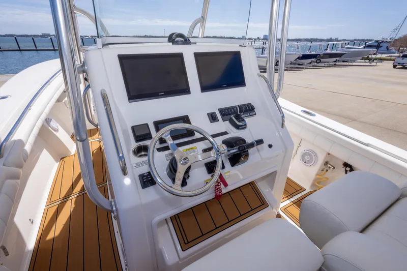 Slide: The Image of 2018 Regulator 31 boat helm with dual screens and modern controls, dockside view. - 33