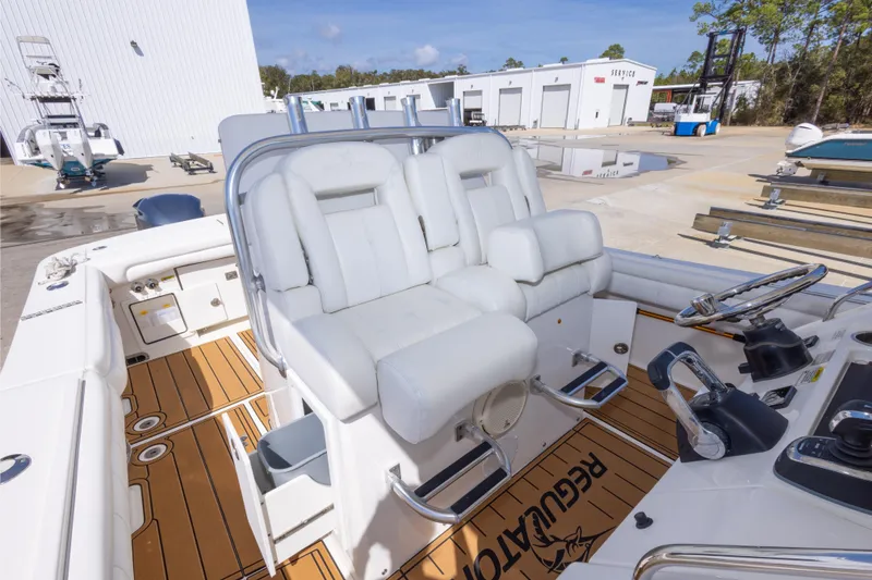 Slide: The Image of 2018 Regulator 31 boat interior with white seating and teak flooring at a marina. - 47