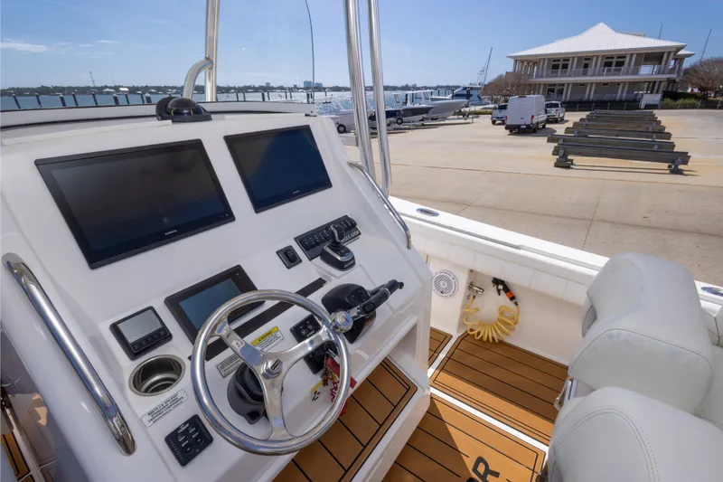 Slide: The Image of 2018 Regulator 31 boat cockpit with dual screens and steering wheel at marina. - 49