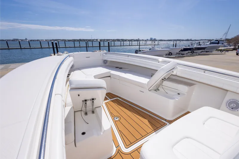 Slide: The Image of 2018 Regulator 31 boat interior with white seating and wooden deck, docked by the water. - 52
