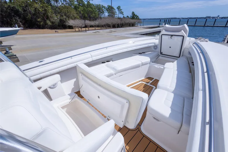 Slide: The Image of 2018 Regulator 31 boat interior with white seating and teak flooring by the water. - 56
