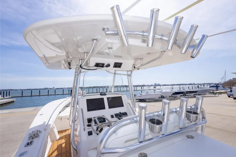 Slide: The Image of 2018 Regulator 31 boat helm with rod holders and dual screens at marina. - 59