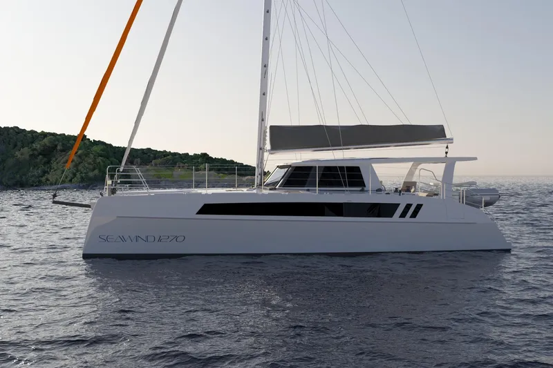 Slide: The Image of 2026 Seawind 1270 catamaran sailing on calm waters near a lush coastline. - 10