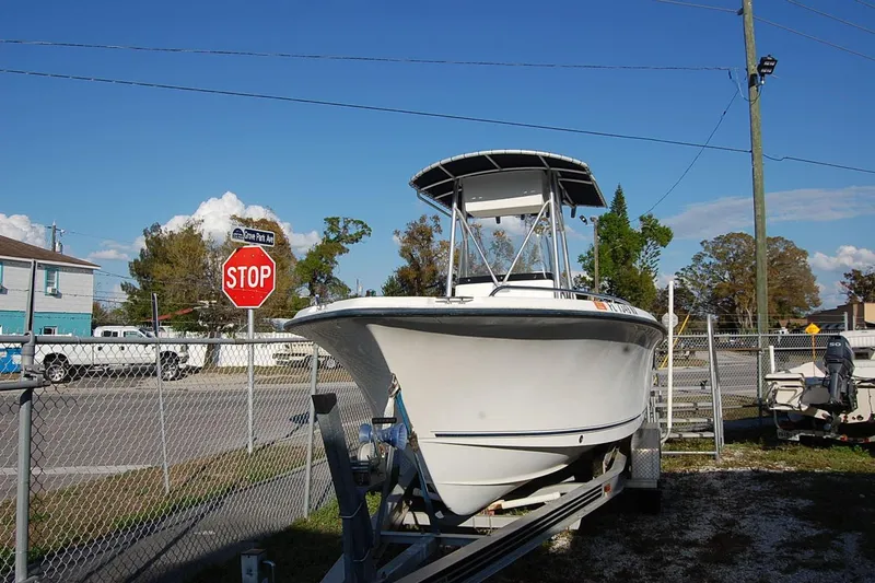 Slide: The Image of 2005 Sea Hunt Triton 220 boat on trailer near stop sign and fence. - 3