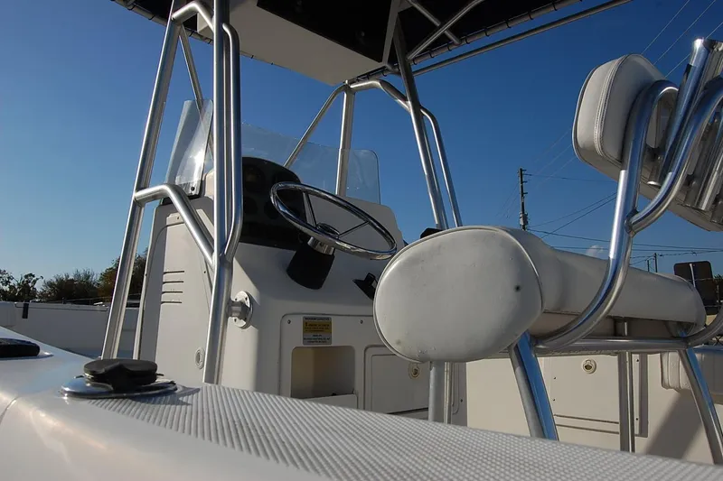 Slide: The Image of 2005 Sea Hunt Triton 220 boat interior with steering wheel and seating, under clear blue sky. - 8