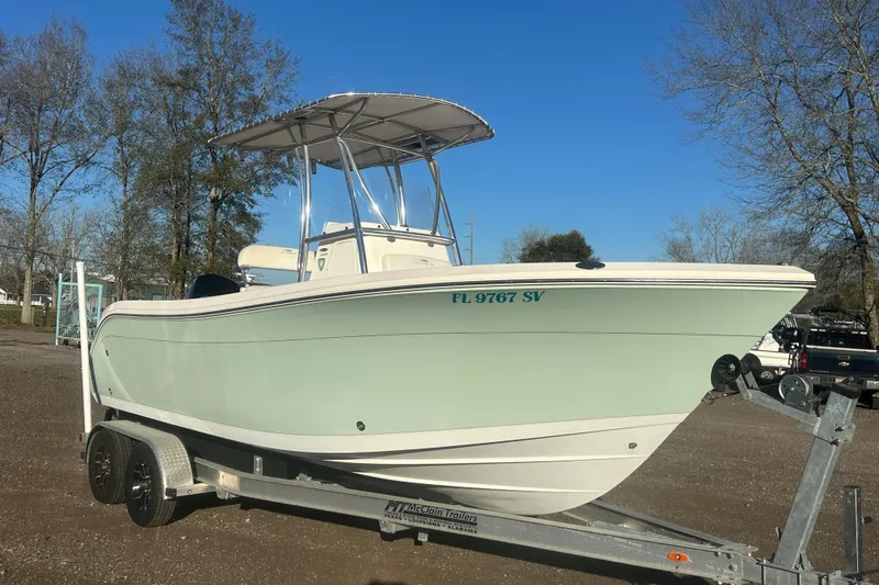The Image of 2021 Cobia 220 Center Console boat on trailer, parked outdoors under clear blue sky. - 0