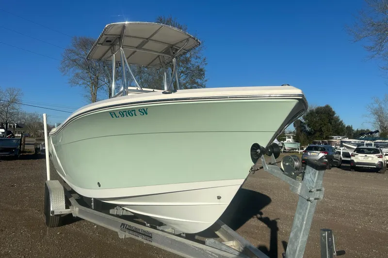 Slide: The Image of 2021 Cobia 220 Center Console boat on trailer, parked outdoors under clear blue sky. - 4