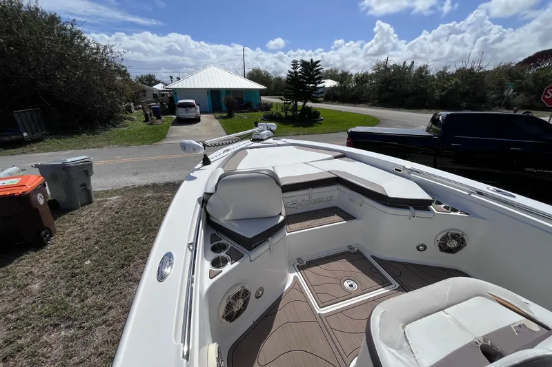 Slide: The Image of 2016 Crevalle 26 Bay boat with seating and cup holders, parked near a residential area. - 14
