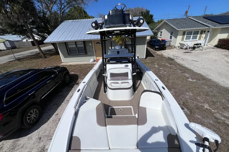 Slide: The Image of 2016 Crevalle 26 Bay boat parked in residential driveway, surrounded by houses and vehicles. - 16