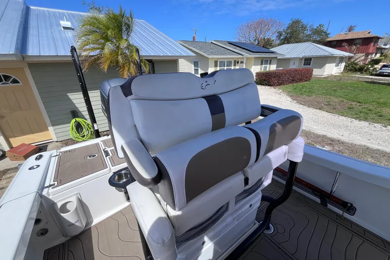 Slide: The Image of 2016 Crevalle 26 Bay boat with cushioned seating, docked near houses and palm tree. - 18
