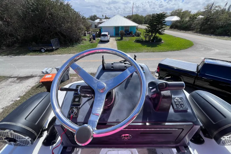 Slide: The Image of 2016 Crevalle 26 Bay boat helm with steering wheel and controls, parked near a residential area. - 21