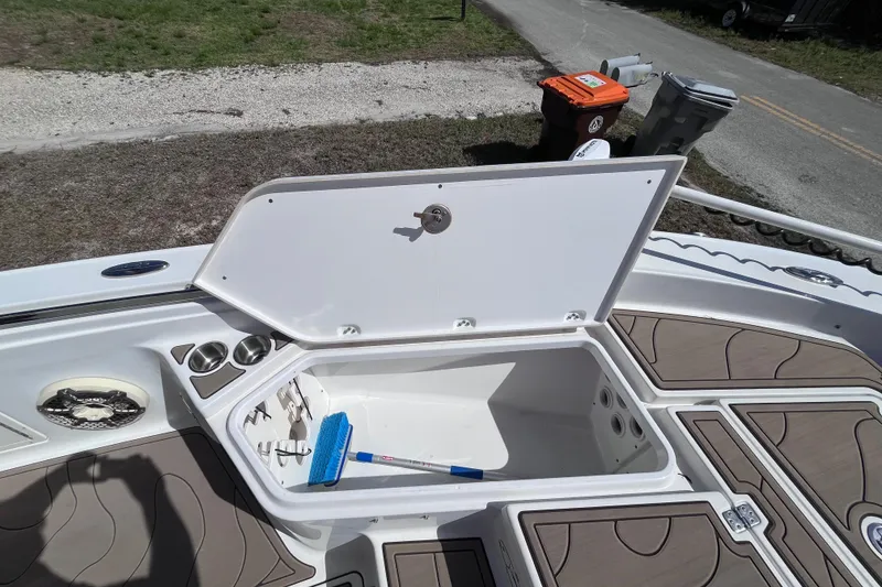 Slide: The Image of Open storage compartment on 2016 Crevalle 26 Bay boat with cleaning brush inside. - 35