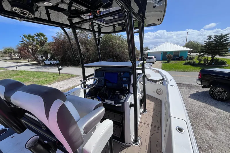 Slide: The Image of 2016 Crevalle 26 Bay boat interior with steering console and seating, parked outdoors. - 9