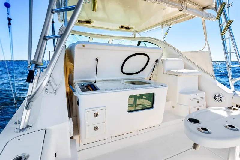 Slide: The Image of 2002 Pursuit 3800 Express boat interior with open storage, ocean view, and fishing equipment. - 23