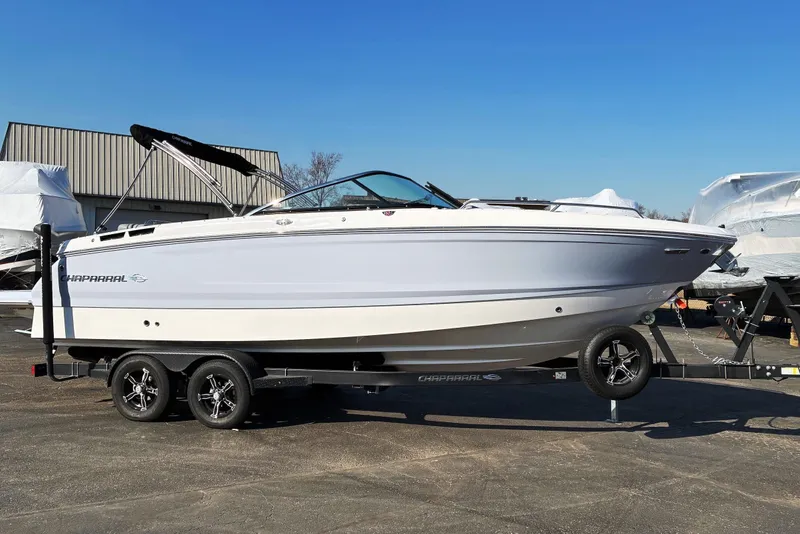 The Image of 2025 Chaparral 267 SSX boat on trailer, parked outdoors under clear blue sky. - 0