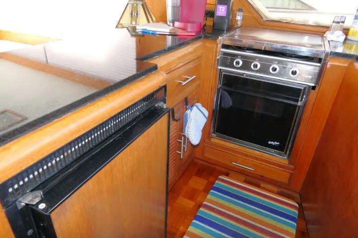 Slide: The Image of 1986 Ocean Alexander 39 Sedan yacht kitchen with stove, wooden cabinetry, and colorful rug. - 17