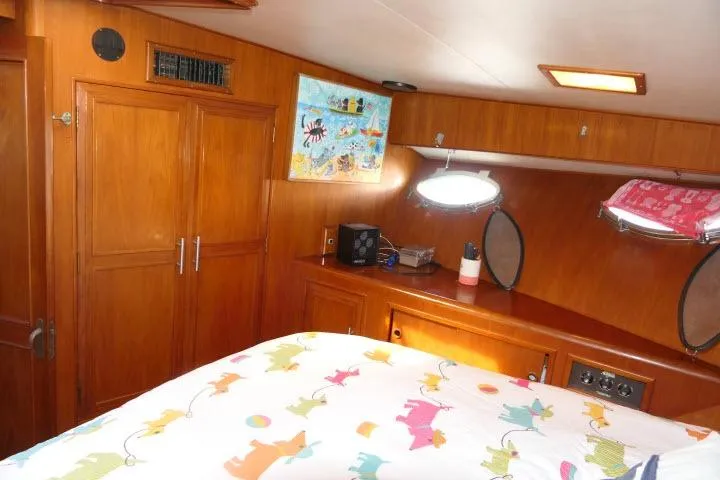 Slide: The Image of 1986 Ocean Alexander 39 Sedan cabin with wooden interior and colorful bedding. - 40
