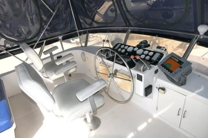 Slide: The Image of 1986 Ocean Alexander 39 Sedan helm with steering wheel, navigation controls, and dual captain chairs. - 45