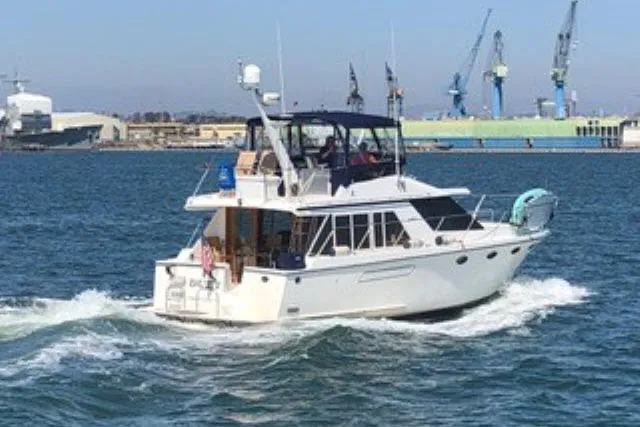 Slide: The Image of 1986 Ocean Alexander 39 Sedan cruising in a harbor with industrial background. - 79