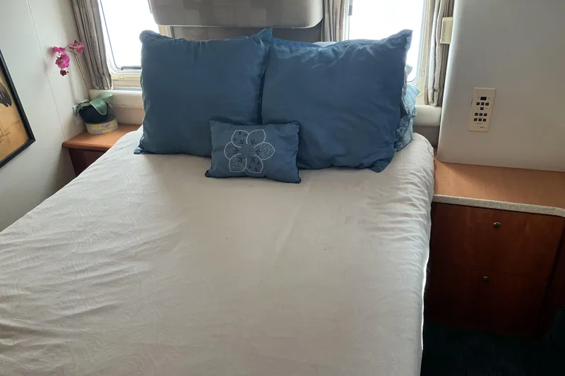 Slide: The Image of Cozy bedroom interior of 1999 Silverton 422 Motor Yacht with blue pillows and wooden cabinets. - 8