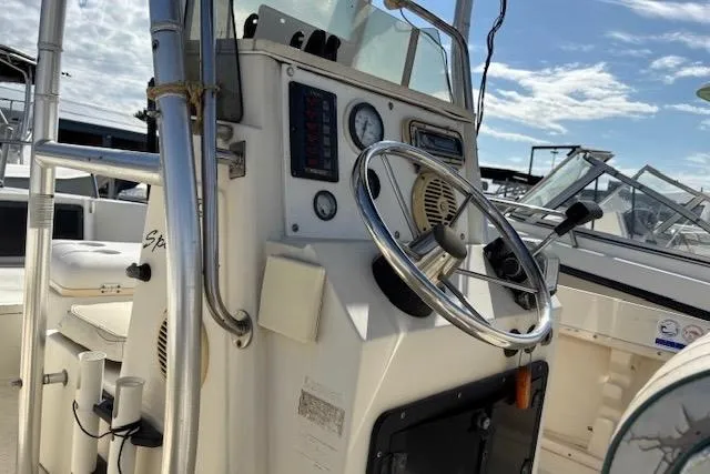 Slide: The Image of 1992 Key West 1900 Sportsman boat console with steering wheel and gauges under a clear sky. - 7