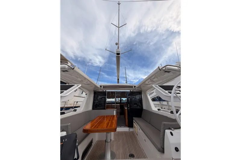 Slide: The Image of 2016 Moody Decksaloon 54 yacht interior with wooden table and seating under a cloudy sky. - 44