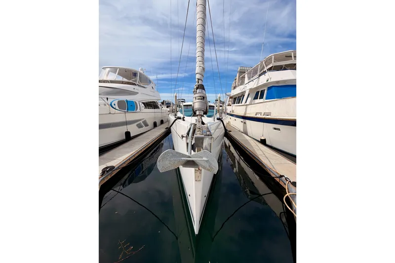 Slide: The Image of Moody Decksaloon 54 yacht docked between boats, 2016 model, under a clear blue sky. - 6