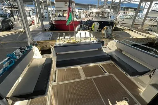 Slide: The Image of 2024 Jeanneau NC 895 Sport docked in a marina, rear view with flags. - 17