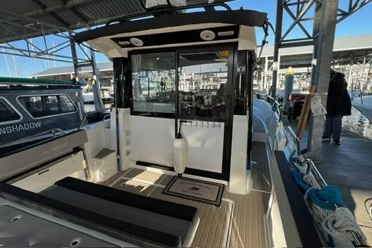 Slide: The Image of 2024 Jeanneau NC 895 Sport boat interior with seating, docked in a marina. - 18