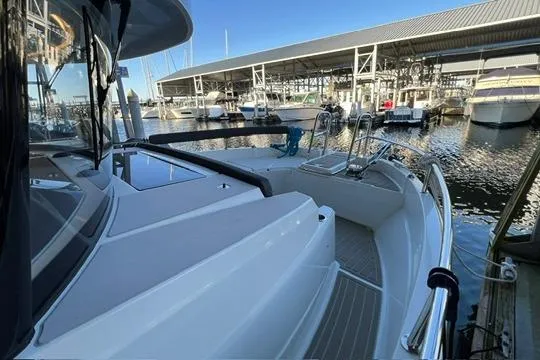 Slide: The Image of 2024 Jeanneau NC 895 Sport boat docked in a marina, rear view. - 19