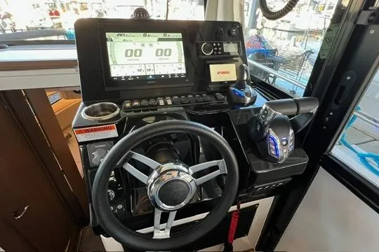 Slide: The Image of 2024 Jeanneau NC 895 Sport boat docked in a marina under a metal roof. - 2
